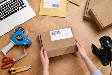 Photo of Post office worker packing parcel at wooden table, top view