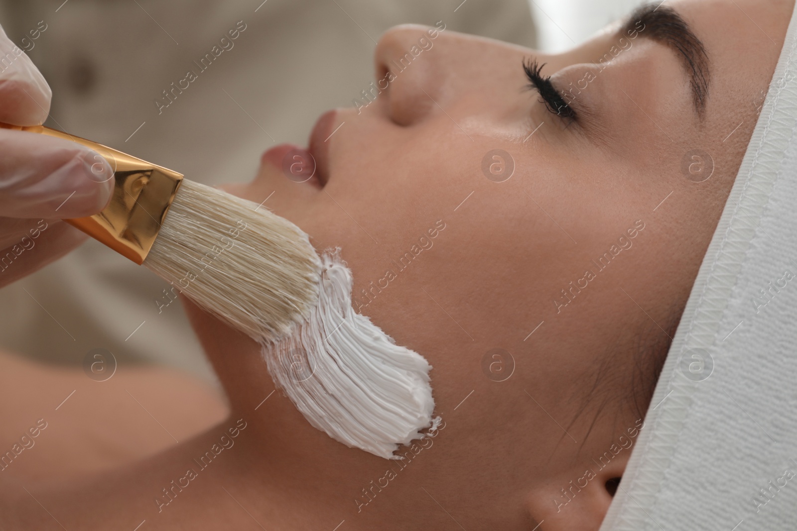 Photo of Young woman during face peeling procedure in salon, closeup