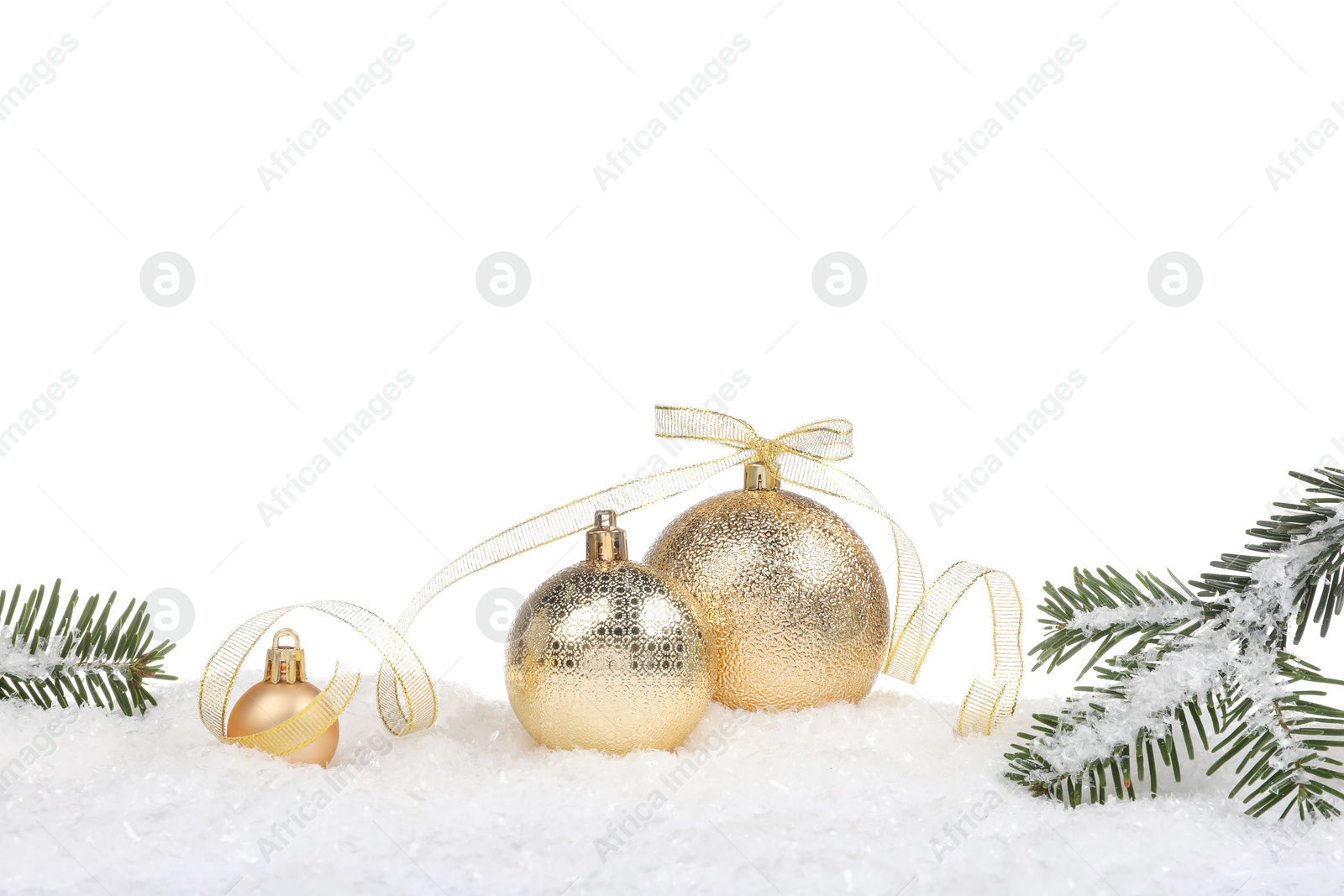 Photo of Beautiful golden Christmas balls with bow and fir tree branches on snow against white background