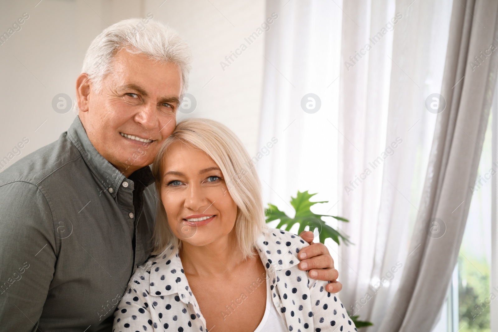 Photo of Portrait of affectionate senior couple at home. Space for text