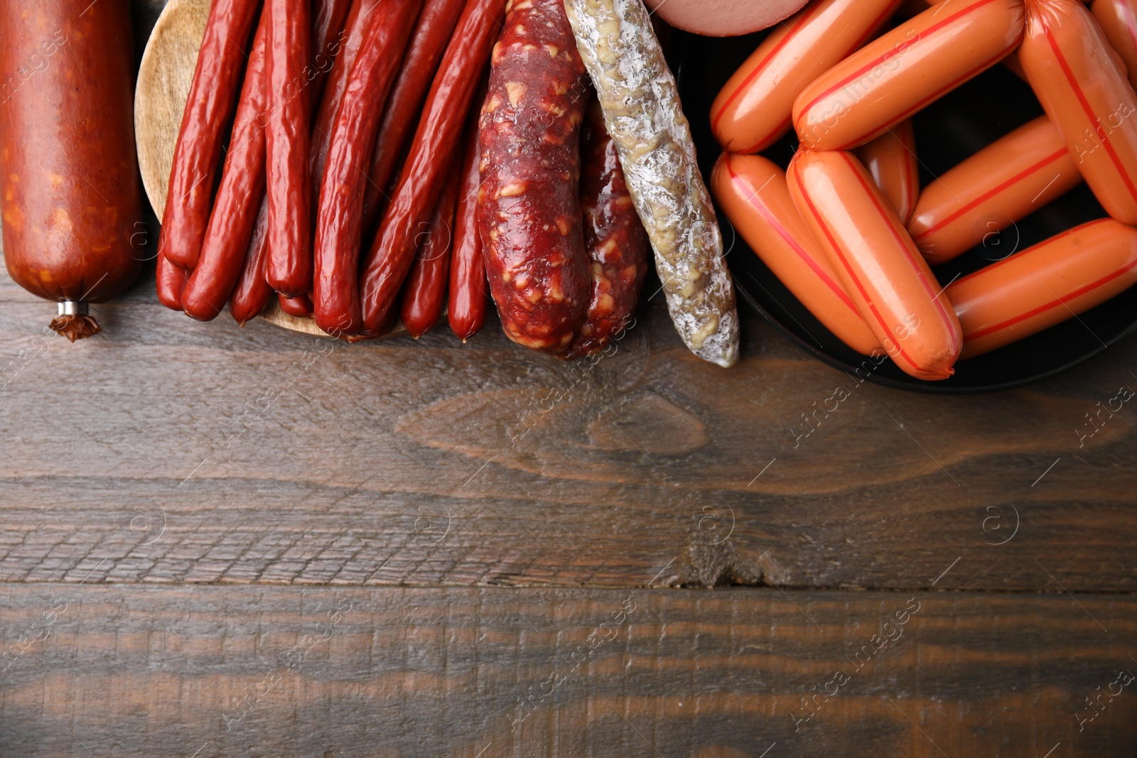 Photo of Different types of sausages on wooden table, flat lay. Space for text