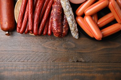 Different types of sausages on wooden table, flat lay. Space for text