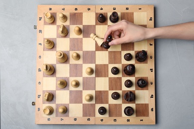 Photo of Woman playing chess on grey background, top view. Victory concept