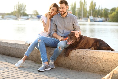 Cute brown labrador retriever with owners outdoors