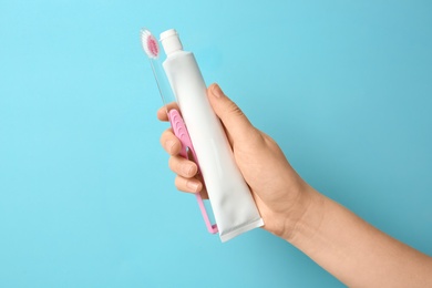 Woman holding toothbrush and paste against color background. Dental care