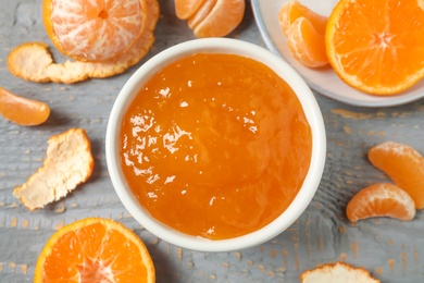 Photo of Flat lay composition with tasty tangerine jam on grey wooden table
