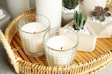 Photo of Wicker tray with burning candles and houseplants on table