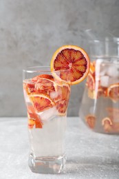 Photo of Delicious refreshing drink with sicilian orange on light grey table