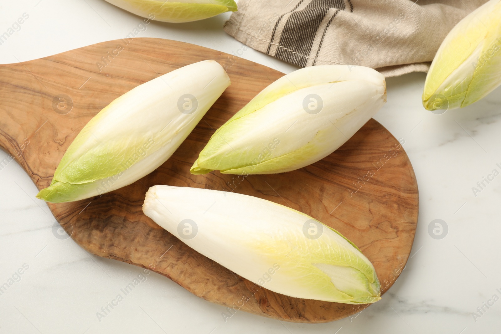 Photo of Raw ripe chicories on white marble table, top view