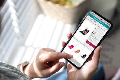 Woman shopping online via smartphone indoors, closeup