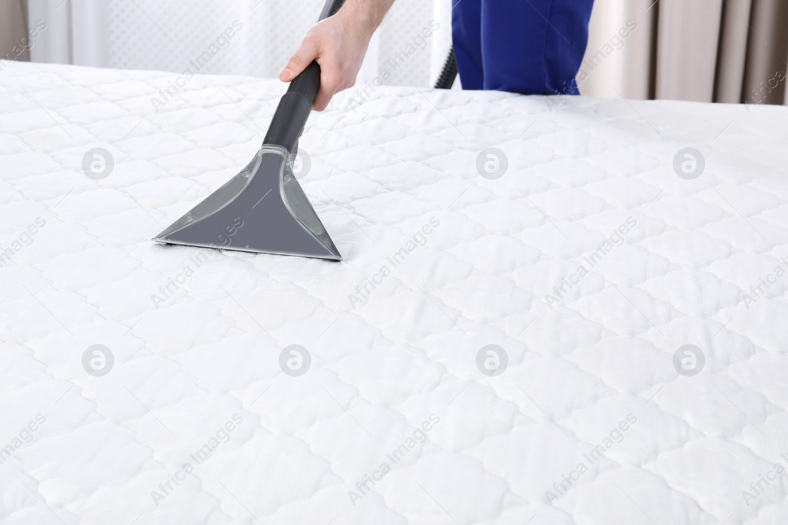 Photo of Man disinfecting mattress with vacuum cleaner, closeup. Space for text