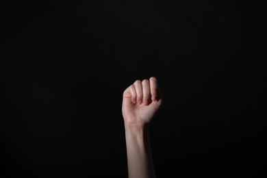 SOS gesture. Woman showing signal for help on black background, closeup