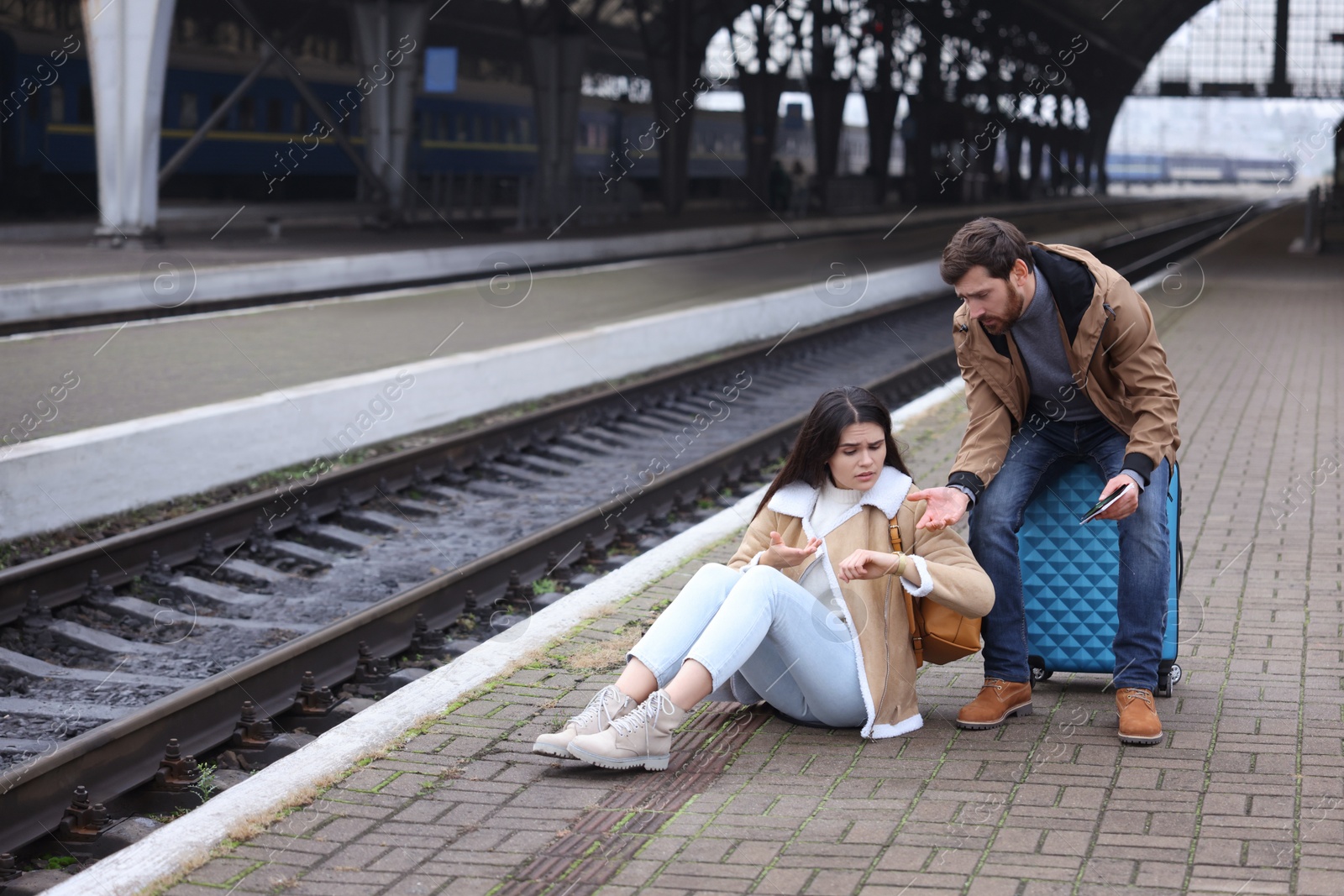 Photo of Being late. Worried couple with suitcase waiting at train station, space for text