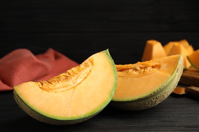 Photo of Tasty fresh cut melon on black wooden table, closeup