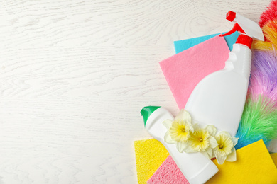 Photo of Flat lay composition with spring flowers and cleaning supplies on white wooden table. Space for text