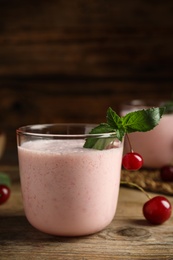 Photo of Tasty fresh milk shake with cherries on wooden table
