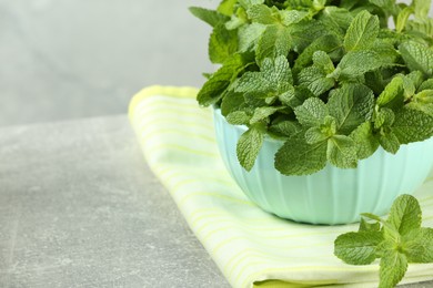 Bowl with fresh green mint leaves on grey table, closeup. Space for text