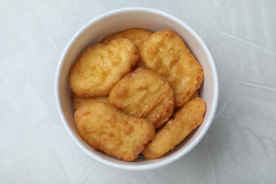 Bucket with tasty chicken nuggets on light grey table, top view