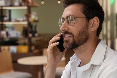 Photo of Handsome man talking on phone in cafe