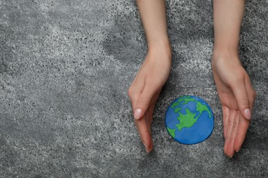 Photo of Happy Earth Day. Woman with plasticine planet at grey table, top view and space for text
