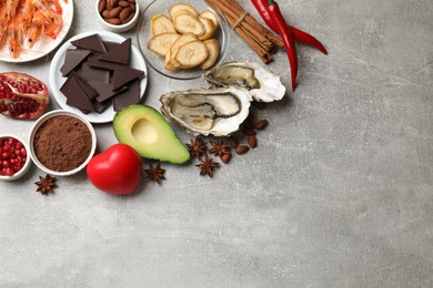 Photo of Natural aphrodisiac. Different food products and heart model on grey table, flat lay. Space for text