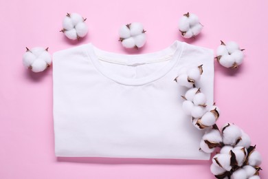 Photo of Cotton branch with fluffy flowers and white t-shirt on pink background, flat lay