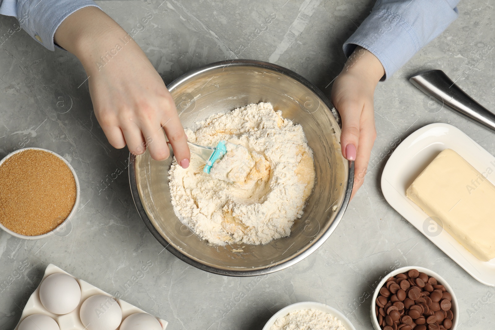 Photo of Cooking chocolate chip cookies. Woman making dough at light grey marble table, top view