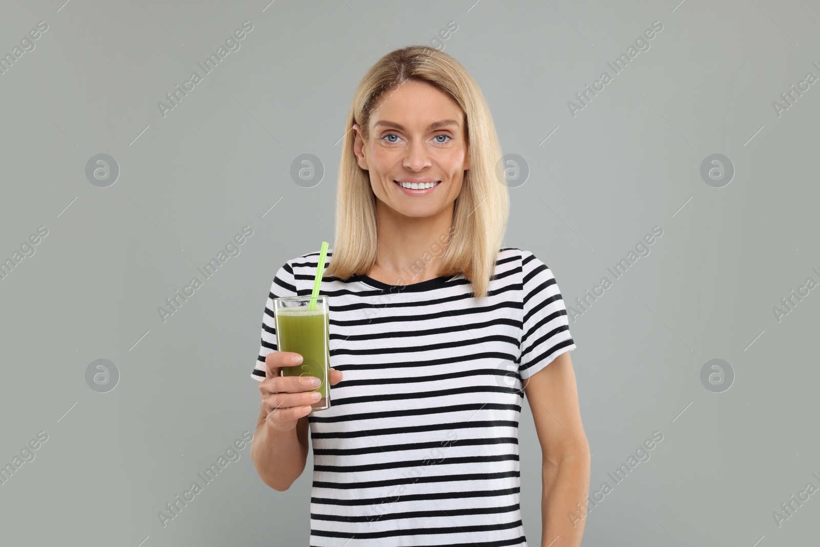 Photo of Happy woman with glass of fresh celery juice on light grey background