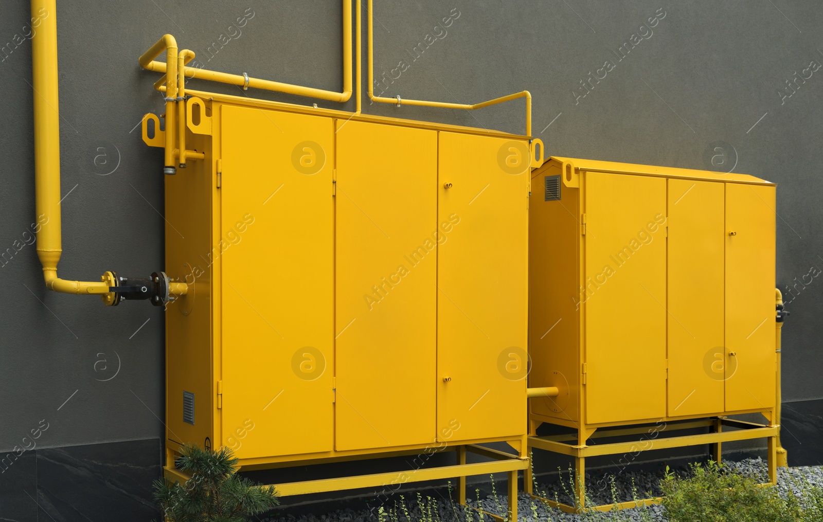 Photo of Yellow gas distribution cabinet near brown wall outdoors