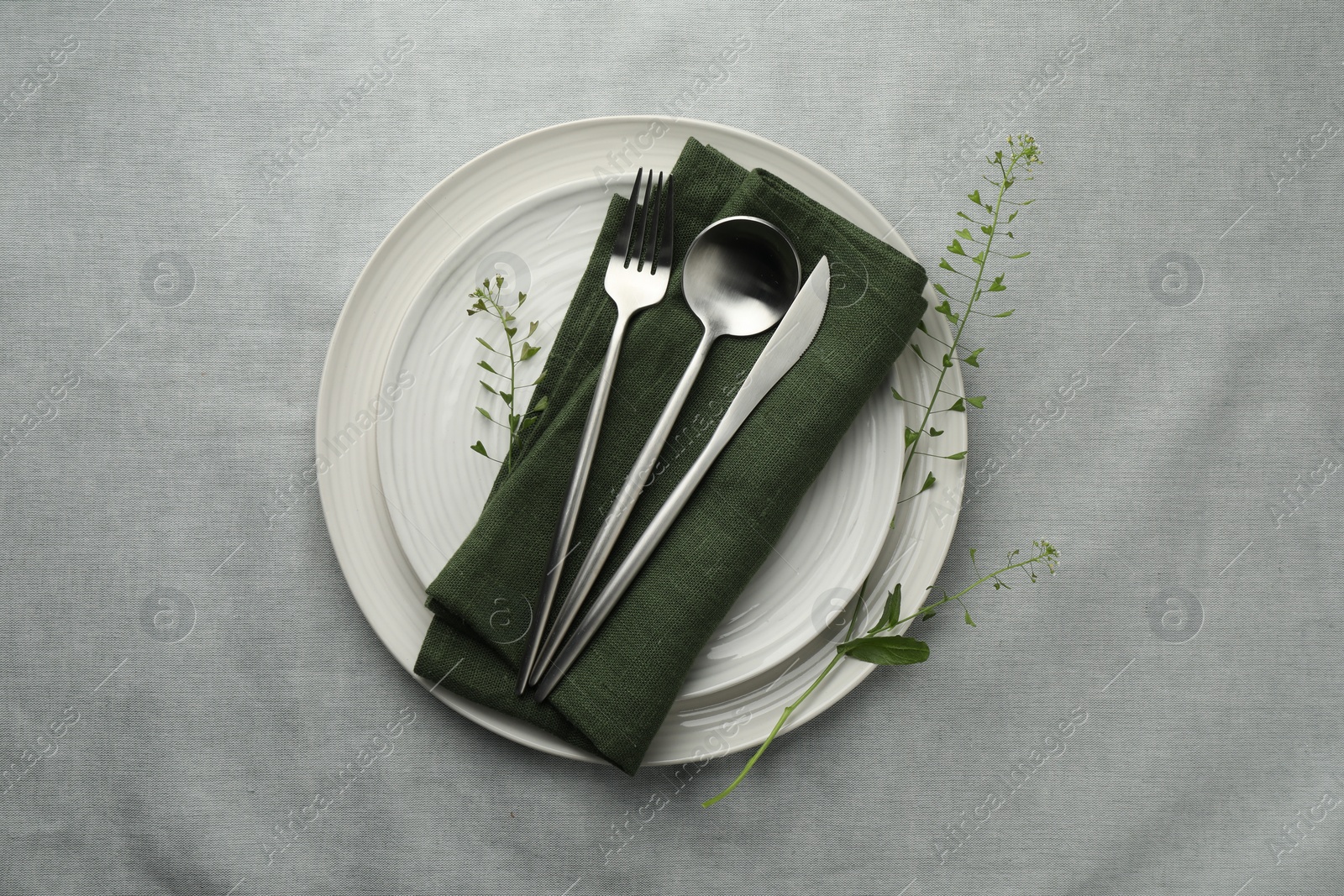 Photo of Stylish setting with cutlery, leaves and plates on grey table, top view