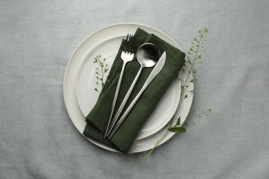 Stylish setting with cutlery, leaves and plates on grey table, top view