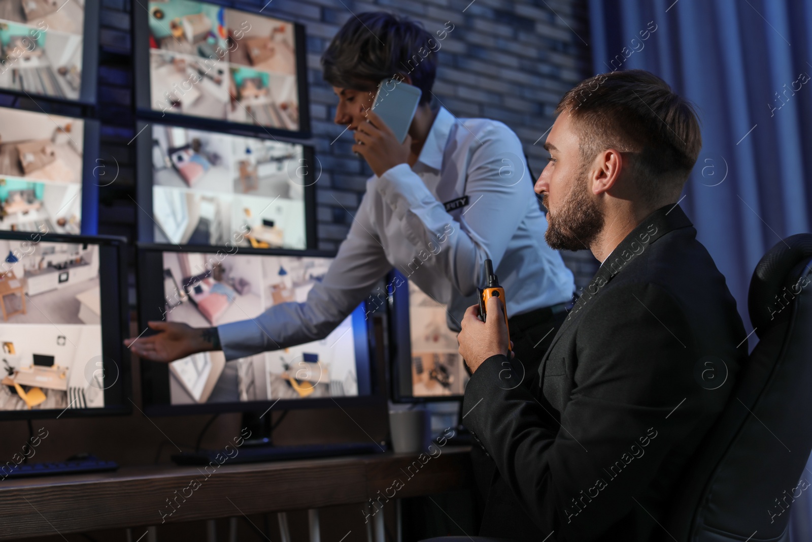 Photo of Security guards monitoring cameras indoors at night