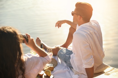 Photo of Woman taking picture of boyfriend on pier at picnic
