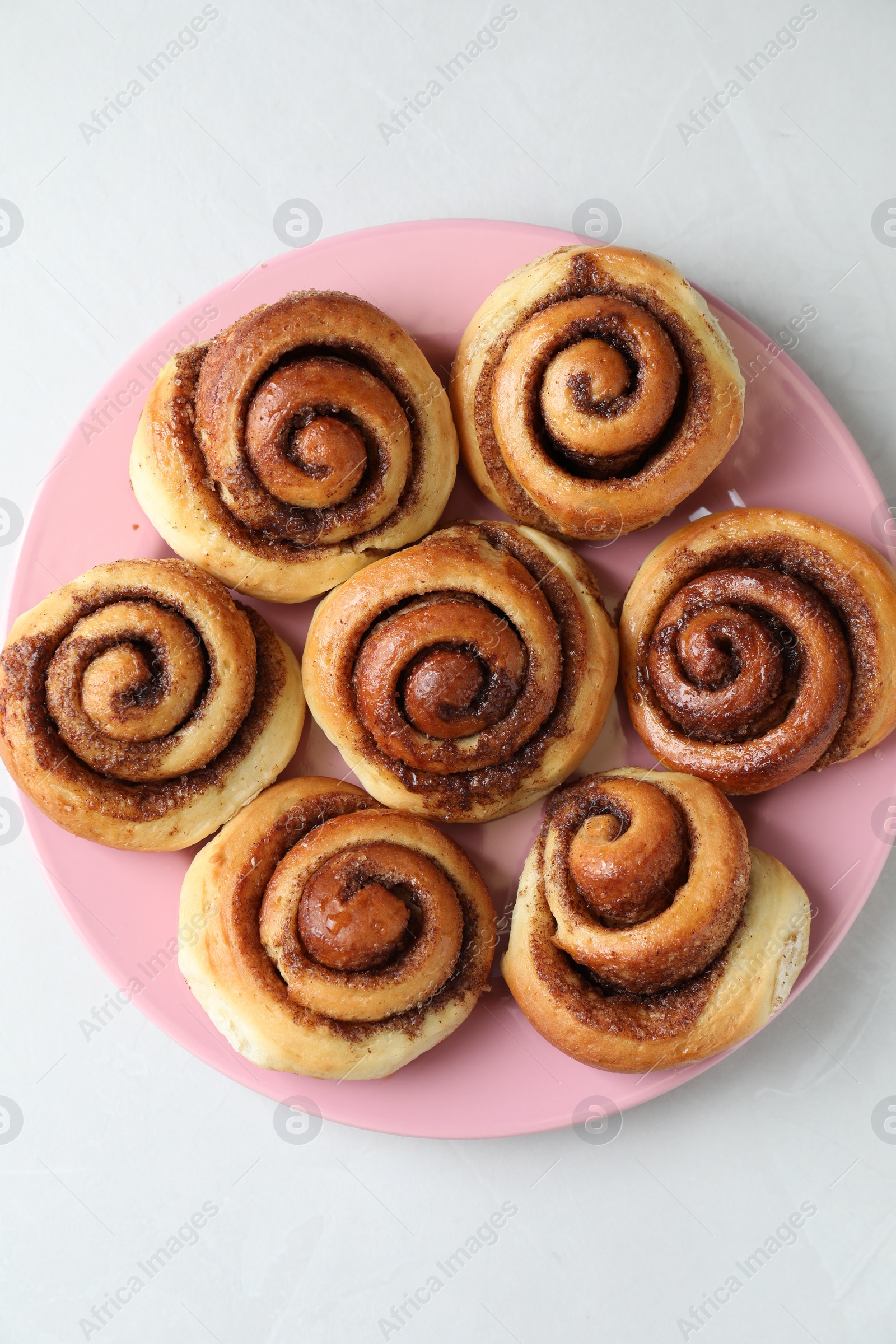 Photo of Many tasty cinnamon rolls on white table, top view