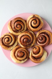 Many tasty cinnamon rolls on white table, top view