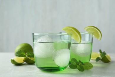 Photo of Delicious cocktails with lime and ice balls on grey table