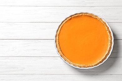 Fresh delicious homemade pumpkin pie on wooden background, top view with space for text