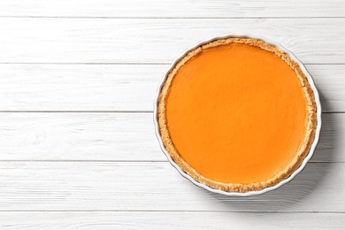 Photo of Fresh delicious homemade pumpkin pie on wooden background, top view with space for text