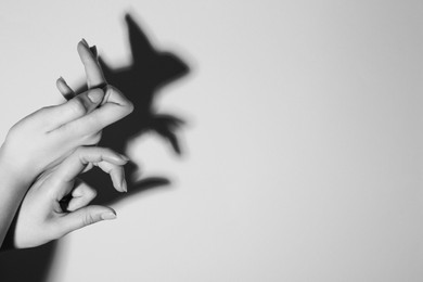 Shadow puppet. Woman making hand gesture like rabbit on light background, closeup with space for text. Black and white effect