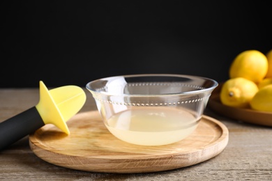 Photo of Freshly squeezed lemon juice and reamer on wooden table