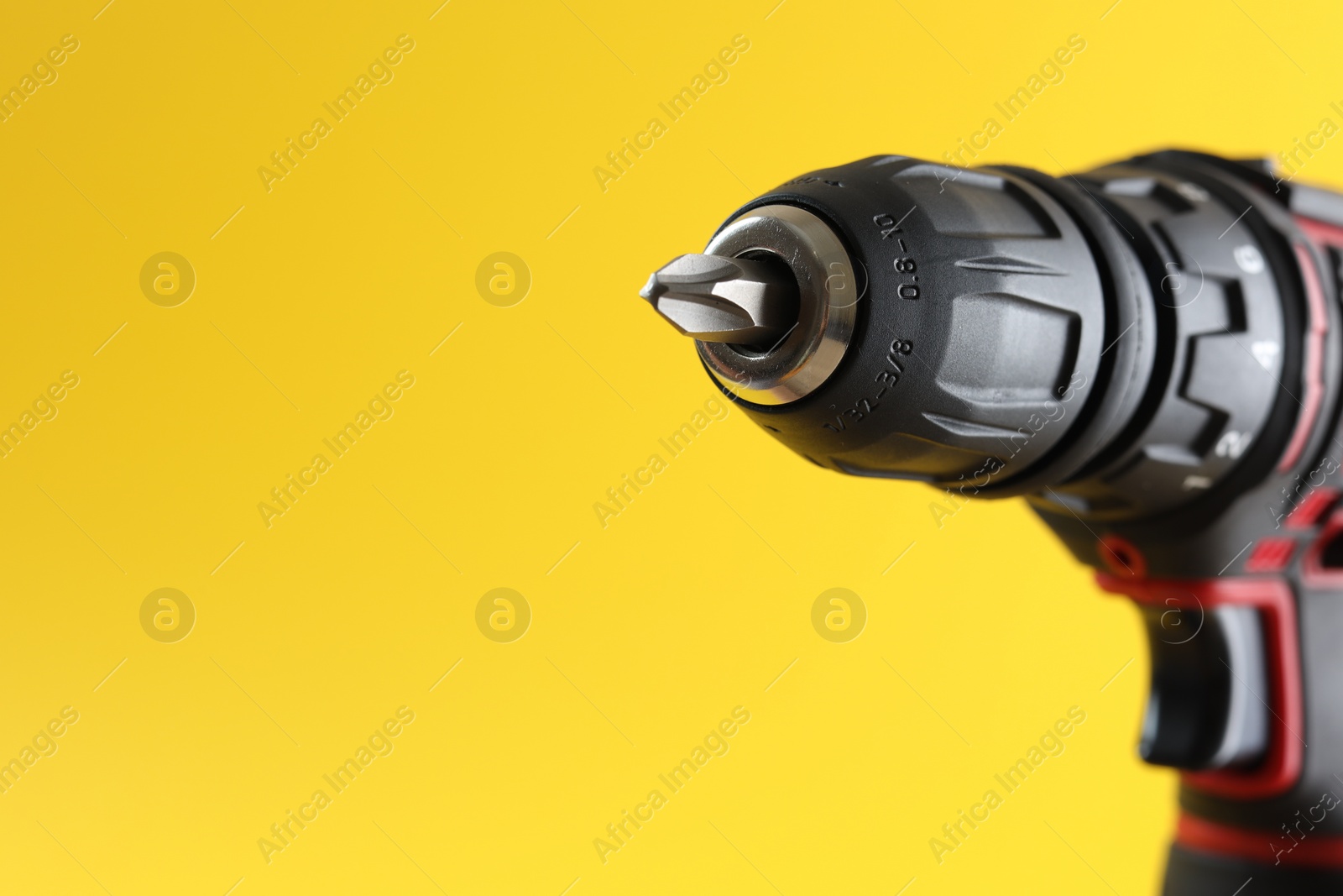Photo of Modern electric screwdriver on yellow background, closeup. Space for text