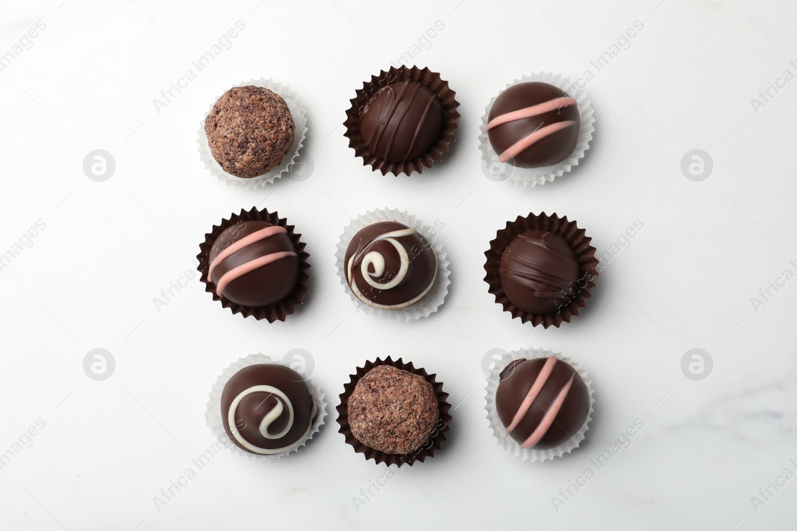 Photo of Different delicious chocolate truffles on white marble table, flat lay