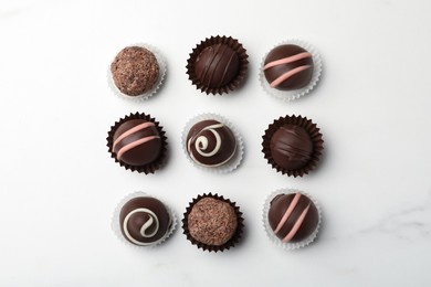 Photo of Different delicious chocolate truffles on white marble table, flat lay