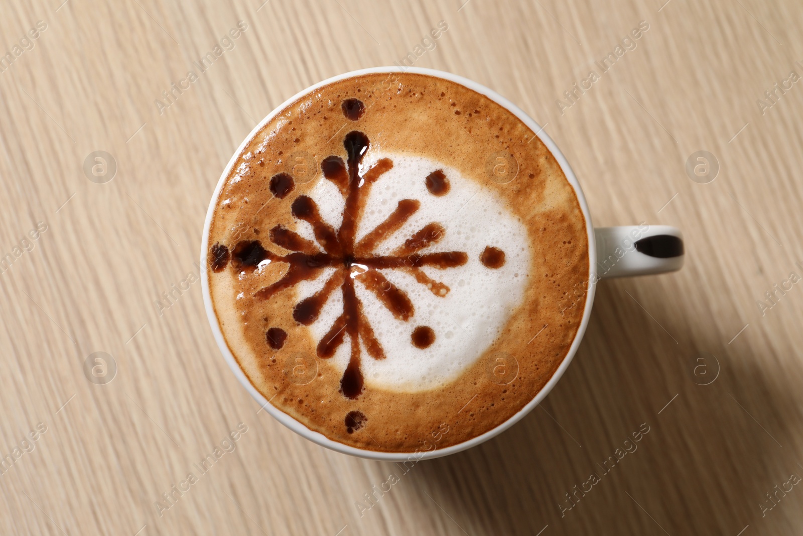 Photo of Cup of aromatic coffee on wooden table, top view