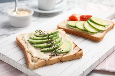 Photo of Slices of bread with different toppings on white wooden board