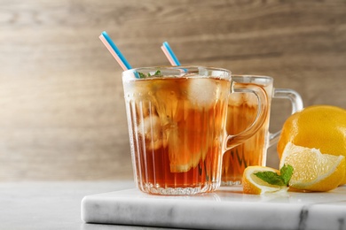 Photo of Cups of refreshing iced tea on table against wooden background