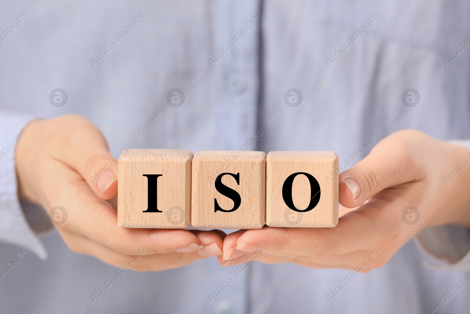 Photo of Woman holding wooden cubes with abbreviation ISO, closeup