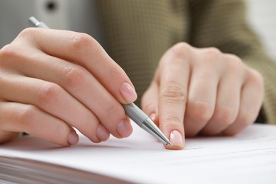 Photo of Woman signing documents on workplace, closeup view