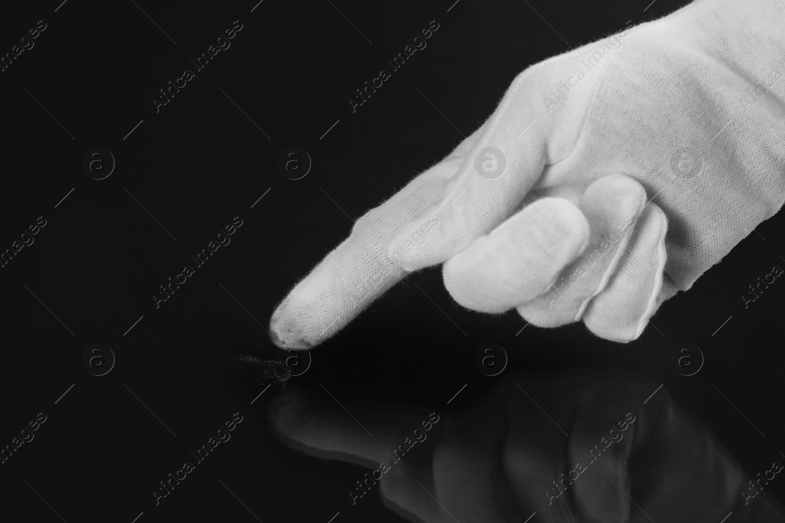 Photo of Person in white glove checking cleanliness of black background, closeup