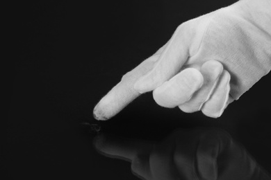 Photo of Person in white glove checking cleanliness of black background, closeup